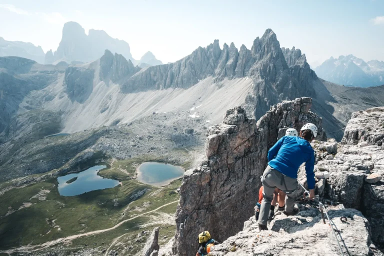 People with climbing gear are descending from the Toblinger Knoten summit, in the Background is the tre cime di lavaredo, Italy