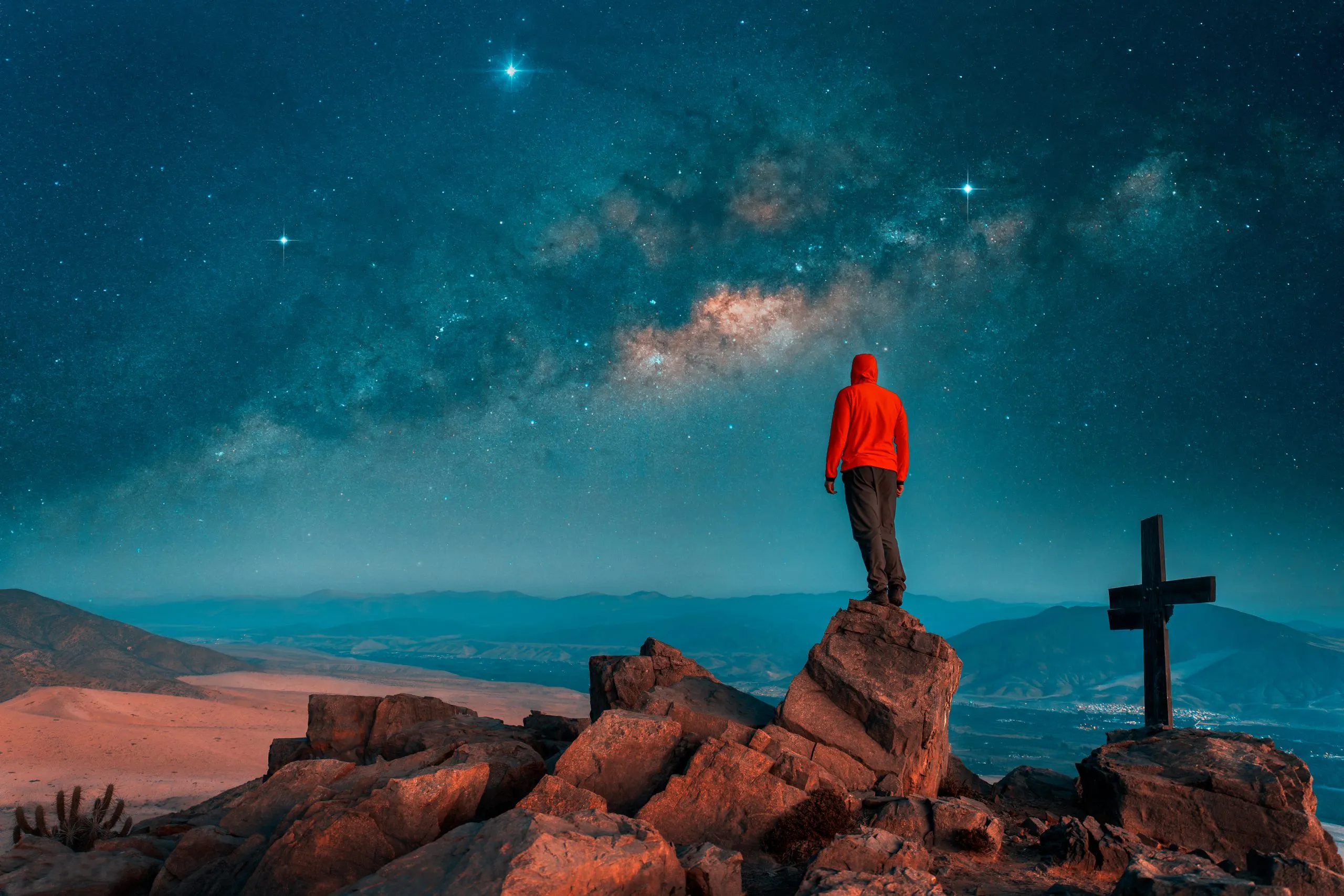 silhouette of a person standing on the top of mountain at night with Milky Way background.